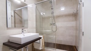 A modern bathroom with a white sink, mirror, and glass-enclosed shower. - Malaga Luxury City Center. Parking (Málaga)