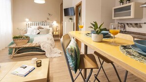 Una habitación de hotel moderna con cama, mesita de noche y zona de comedor con mesa y sillas.
