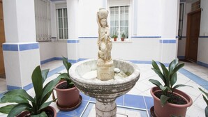 Un patio con una fuente de piedra, plantas en macetas y una estatua.