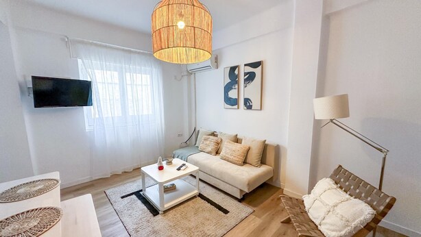 Una sala de estar moderna con sofá, mesa de centro y lámpara colgante.
