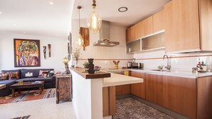 Cozinha moderna com armários de madeira, uma ilha central e iluminação pendente.