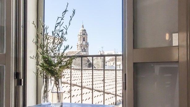 Uma varanda com vista para um edifício com cúpula e torre sineira.