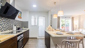 A modern kitchen with a large island, wooden cabinets, and a tiled backsplash. - Malaga Exclusive Beach Apartment with Terrace (Málaga)
