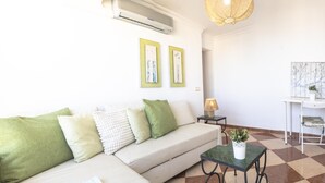A living room with a sofa, a coffee table, a lamp, and a potted plant. - Apartamento con Balcon. Free Parking (Málaga)