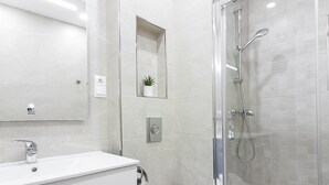 Ein modernes Badezimmer mit einer Duschkabine aus Glas, einem weißen Waschbecken und einer Toilette.