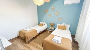 Ein Hotelzimmer mit zwei Betten, einem kleinen Tisch und einer Wand-Klimaanlage.