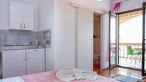 A bedroom with a bed, a bathroom, and a kitchen area. - Studio Paula 1 300m From Sea (Crikvenica)