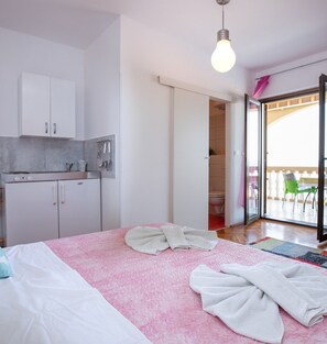 Un dormitorio con cama, baño y zona de cocina.