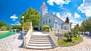A historic building with a prominent clock tower, a stone staircase leading to the entrance, and a surrounding garden with a small bridge over a body of water. - Studio Paula 1 300m From Sea (Crikvenica)