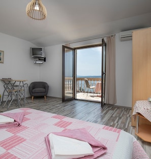 Een hotelkamer met een bed, een bureau, een stoel en een televisie. De kamer heeft uitzicht op het strand.