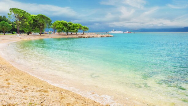 A beach with clear turquoise water, sandy shore, and green trees. - Studio Paula 5 300m From Sea (Crikvenica)
