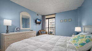 A bedroom with a large bed, dresser, mirror, TV, and window with a view of buildings. - 2 Bedroom, 2 Bath Side Unit with fantastic views of the ocean and pool (Ocean City)