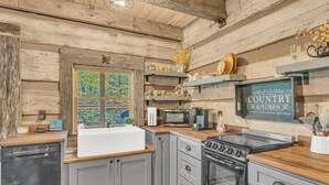 Een rustieke keuken met houten wanden, een groot raam en een bordje met de tekst 'Country Kitchen'.