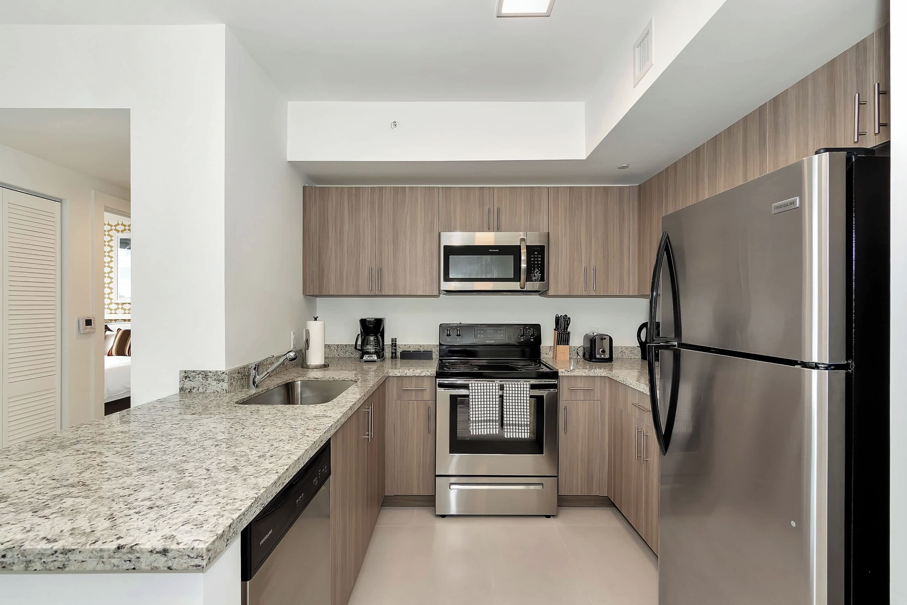 A modern kitchen with granite countertops, stainless steel appliances, and wooden cabinetry.