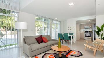 A modern living room with a sofa, a coffee table, and a dining area with chairs.