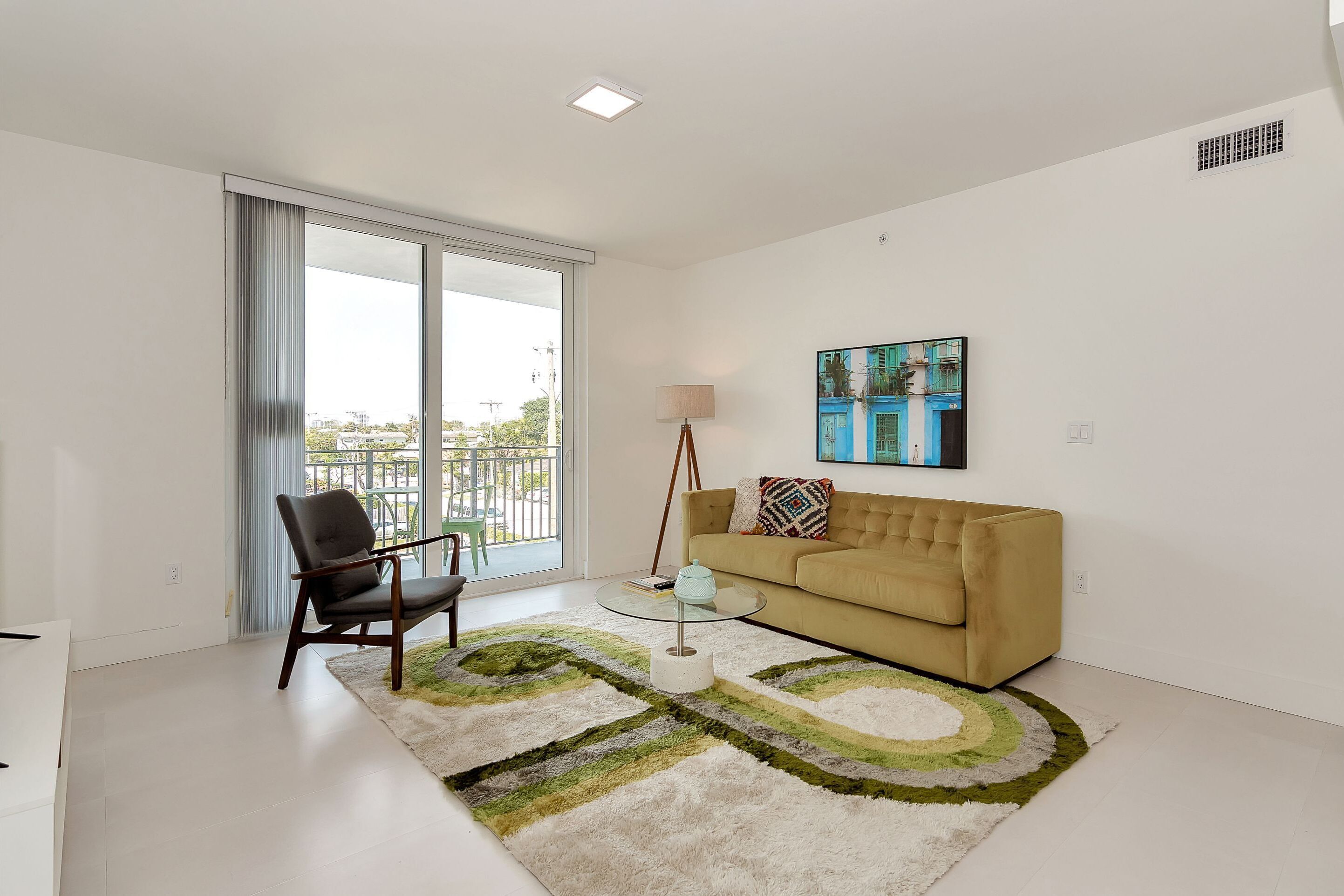 Ein modernes Wohnzimmer mit Sofa, Sessel, Couchtisch und einem Gemälde an der Wand.