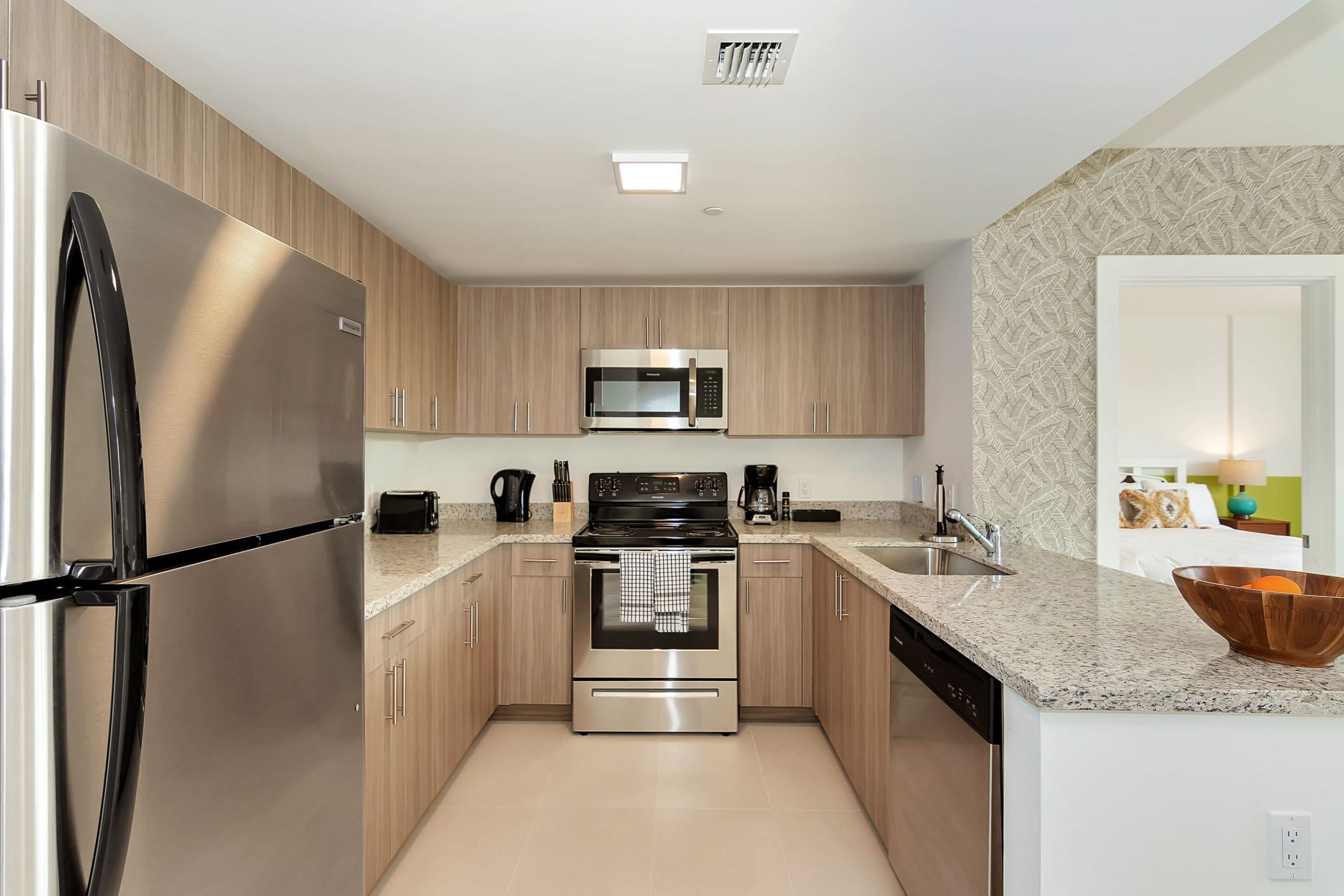 A modern kitchen with stainless steel appliances, wooden cabinets, and granite countertops.