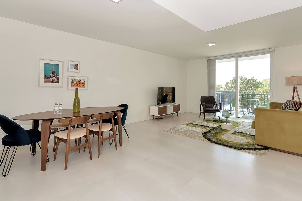 Un salon moderne comprenant un coin repas, un téléviseur et un balcon avec vue.