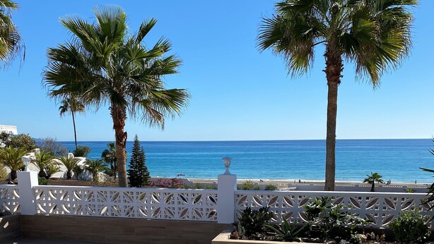 A terrace with lounge chairs and a view of the sea.