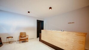 Un'area reception con una scrivania in legno, due sedie e una porta.