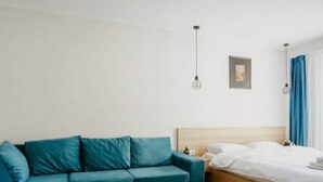 Una camera da letto moderna con un divano color petrolio, un letto in legno e un arredamento minimalista.