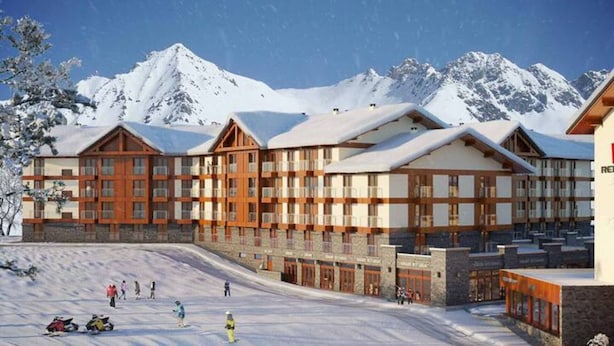 Edificio di una stazione sciistica con diversi piani, ampie finestre e una montagna innevata sullo sfondo.