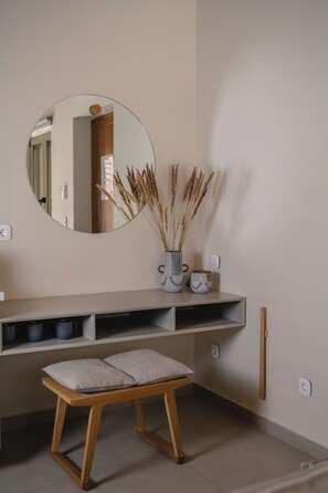 Un bany amb un mirall rodó, un lavabo amb una barra de sabó, un suport de tovalloles i una banca.