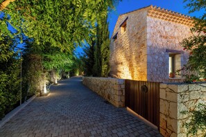A stone pathway leading to a rustic building with a wooden door and a small window.