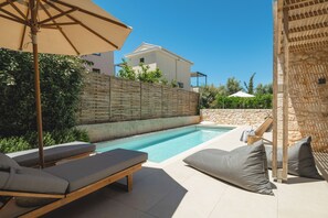 A swimming pool with lounge chairs and a stone wall.