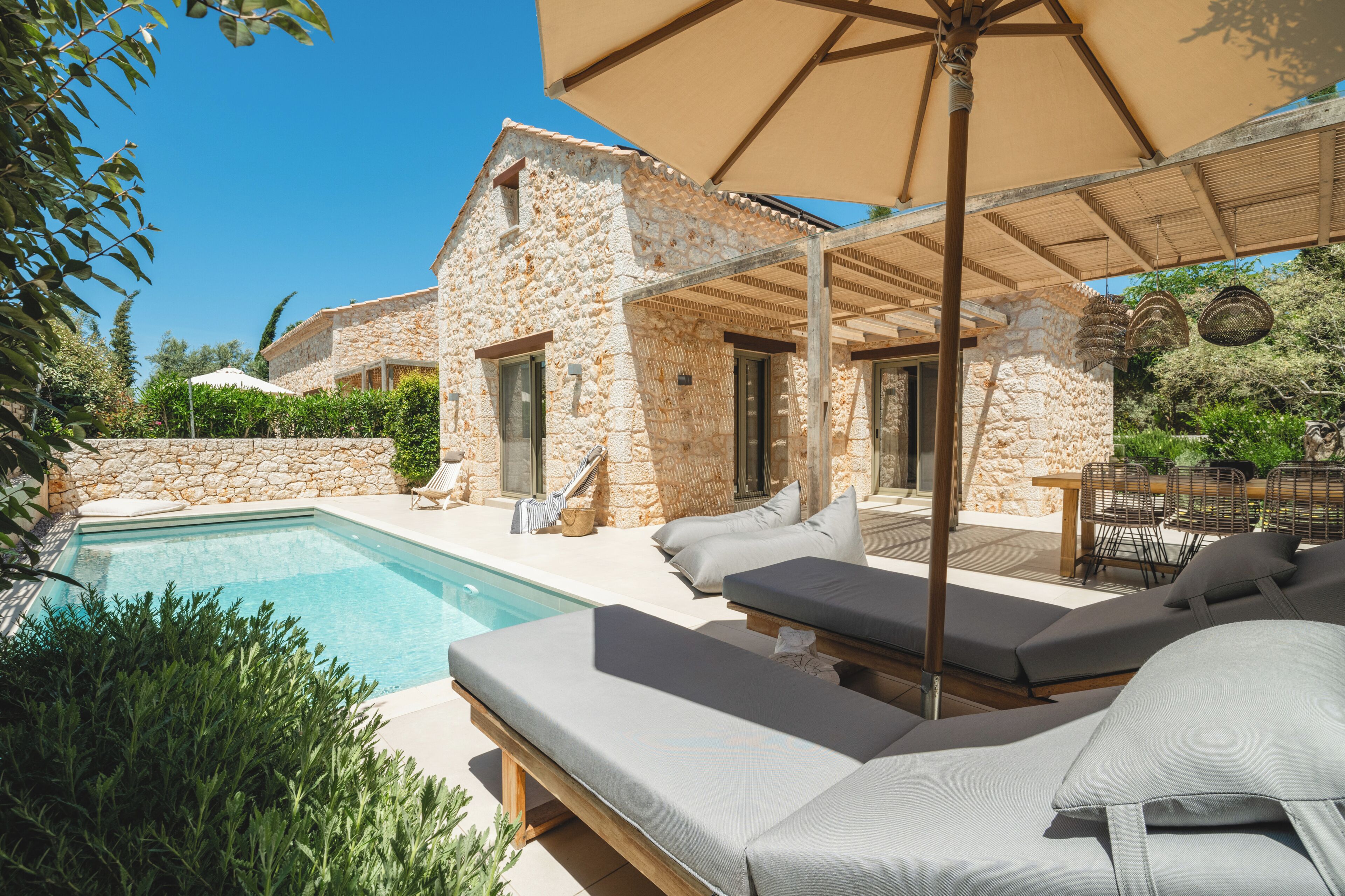 Une villa en pierre dotée d’une piscine, d’un espace salon extérieur et d’une pergola.