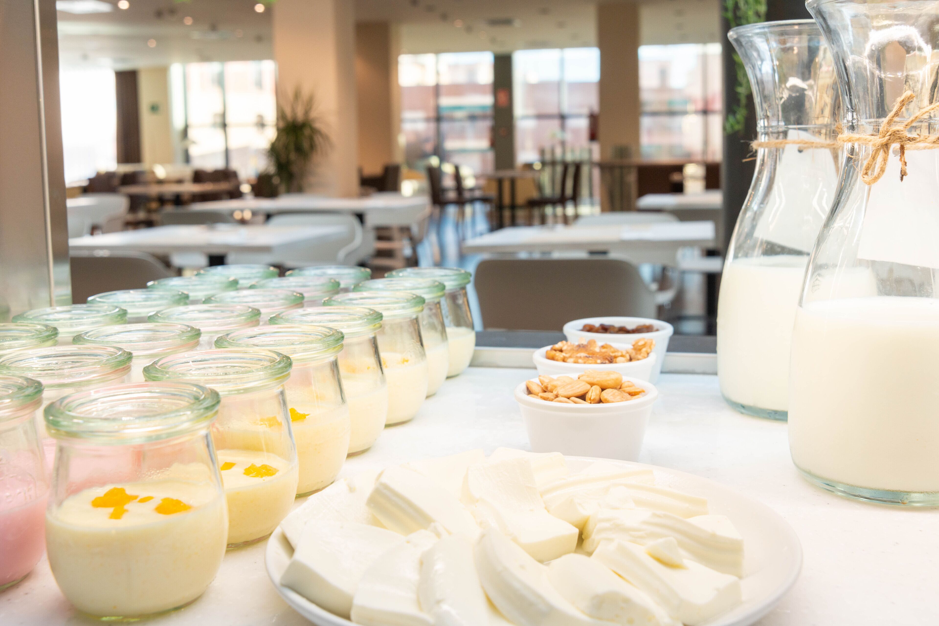 A buffet table with various dairy products, including jars of milk and cheese, and a pitcher of milk.