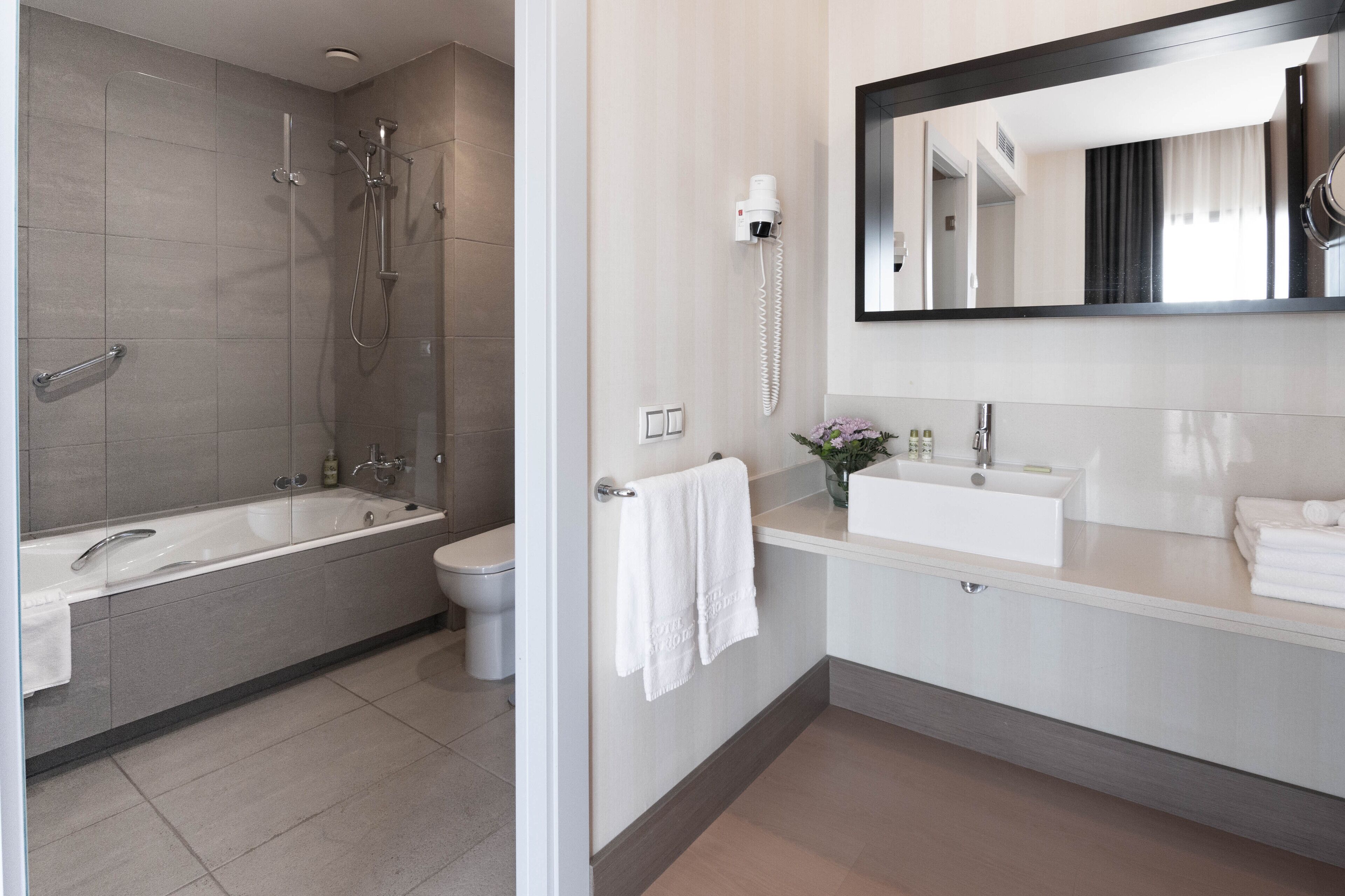 Une salle de bain moderne équipée d’une baignoire, d’une douche, de toilettes et d’un meuble-lavabo avec un évier et un miroir.