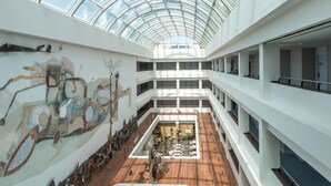 Een atrium met meerdere niveaus, een glazen dak, houten vloeren en een centrale binnenplaats.