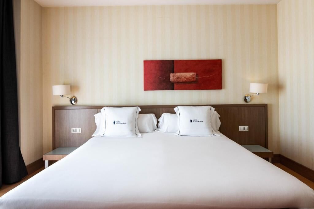 A hotel room with a large bed, two bedside tables, and a wall-mounted artwork.