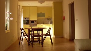 Uma cozinha moderna com armários amarelos, uma mesa de jantar com cadeiras e uma luminária pendente.