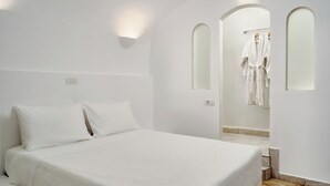 Un dormitorio con una cama grande, una mesita de noche y un vestidor con espejo y bata.