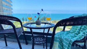 Ein Balkon mit Korbstühlen, einem kleinen runden Tisch und einer Vase mit Blumen.