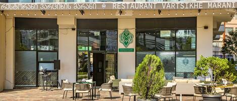 A restaurant with outdoor seating and a sign in a foreign language.