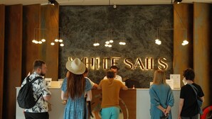 Una mesa de recepción con un letrero que dice "WHITE SAILS" y una persona detrás.