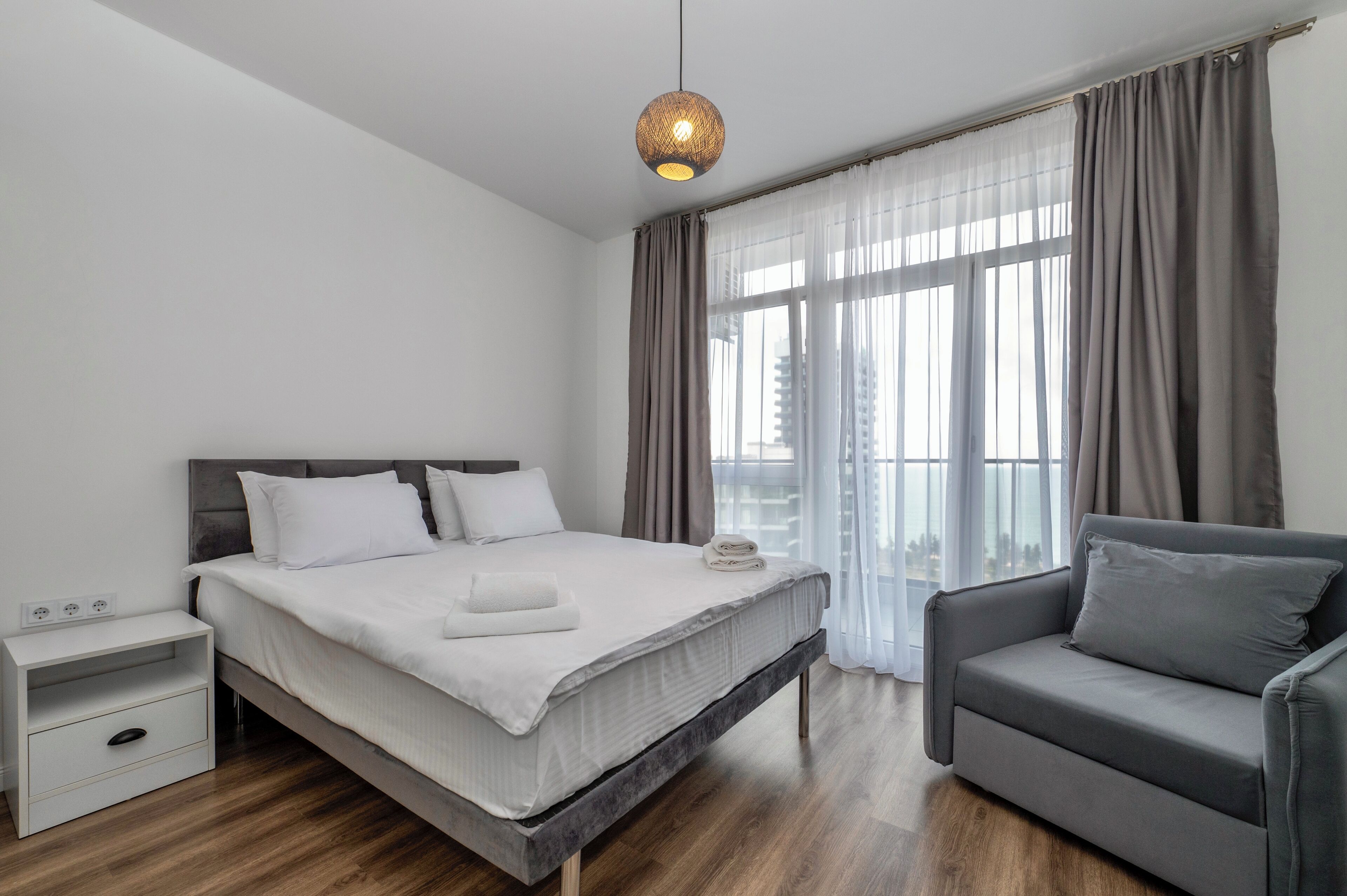Ein modernes Schlafzimmer mit Bett, Nachttisch und einem grauen Sofa.