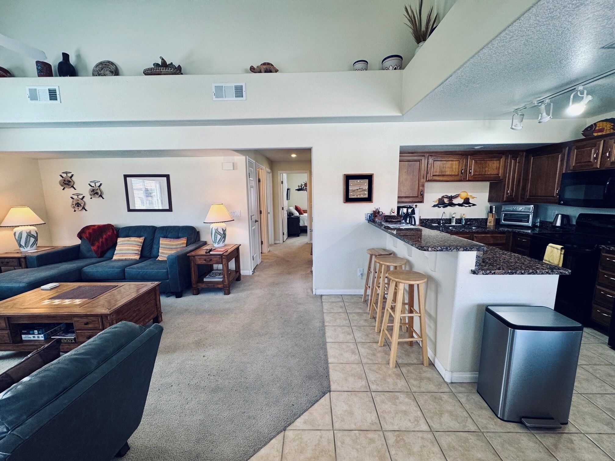 A spacious living area with a sofa, coffee table, and a kitchen with a bar area.