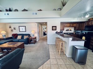 A spacious living area with a sofa, coffee table, and a kitchen with a bar area. - Fox Run | 3BR Near Wolf Creek + Free Activities (Mesquite)