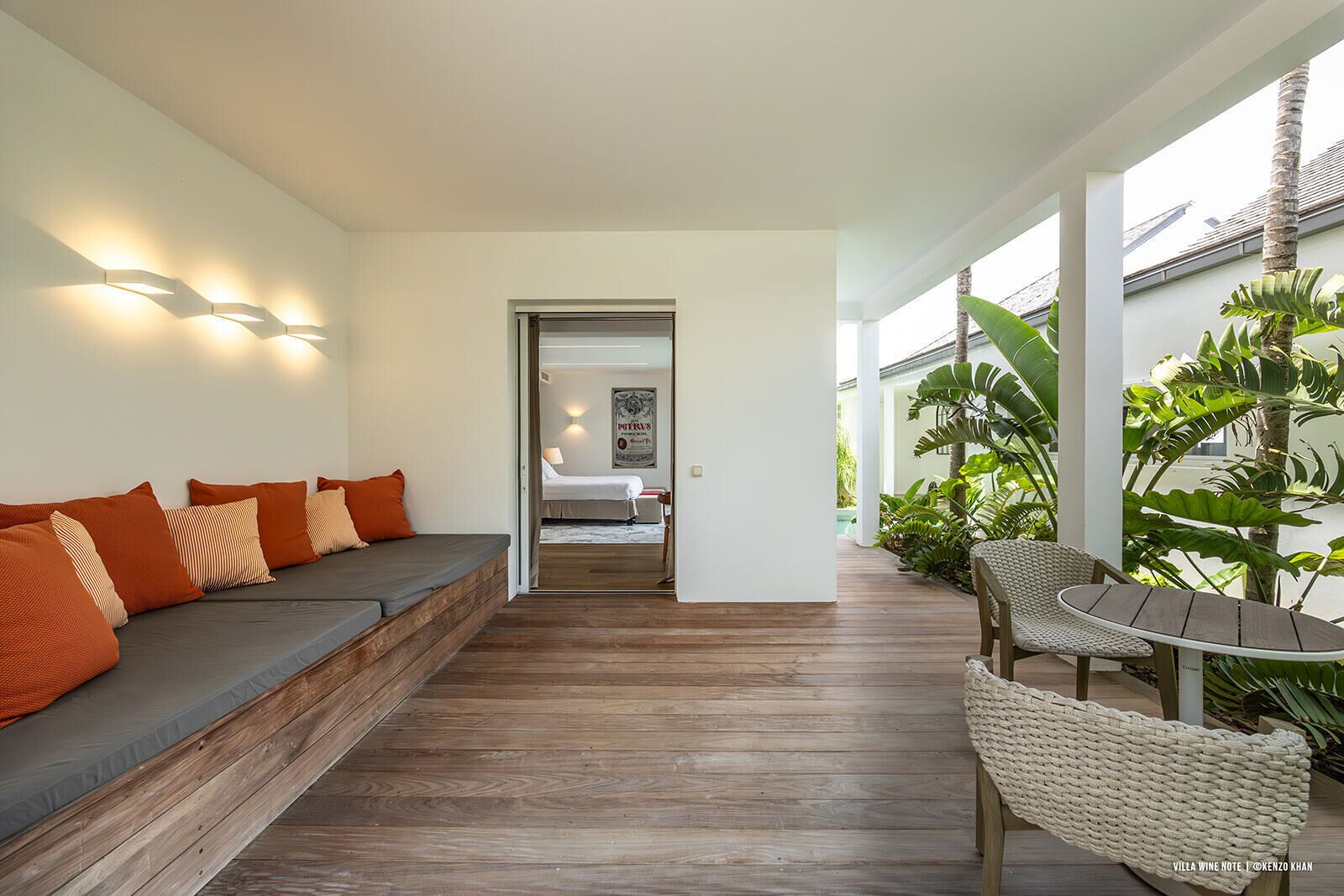 Um interior moderno com piso de madeira, um sofá com almofadas laranja e uma cadeira de vime.