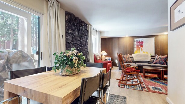 A modern living room with a wooden dining table, a red armchair, a sofa, and a large window. - Central Location, Restaurants & Shops. Tennis Courts, Hot Tub & Pool On-site (Mammoth Lakes)