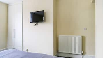 A bedroom with a bed, a wardrobe, a television mounted on the wall, and a radiator.