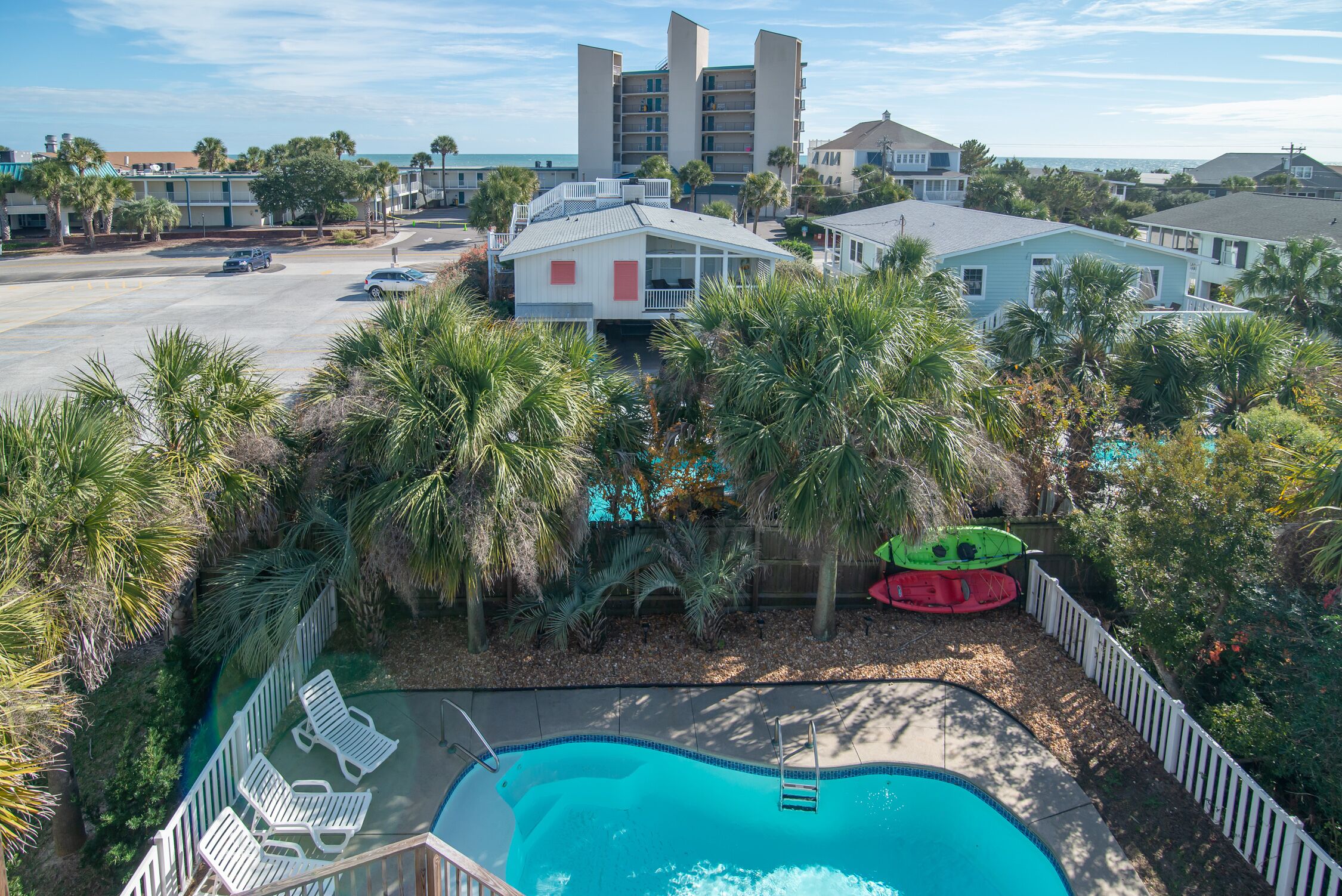 A hotel with a swimming pool, palm trees, and a view of the ocean.