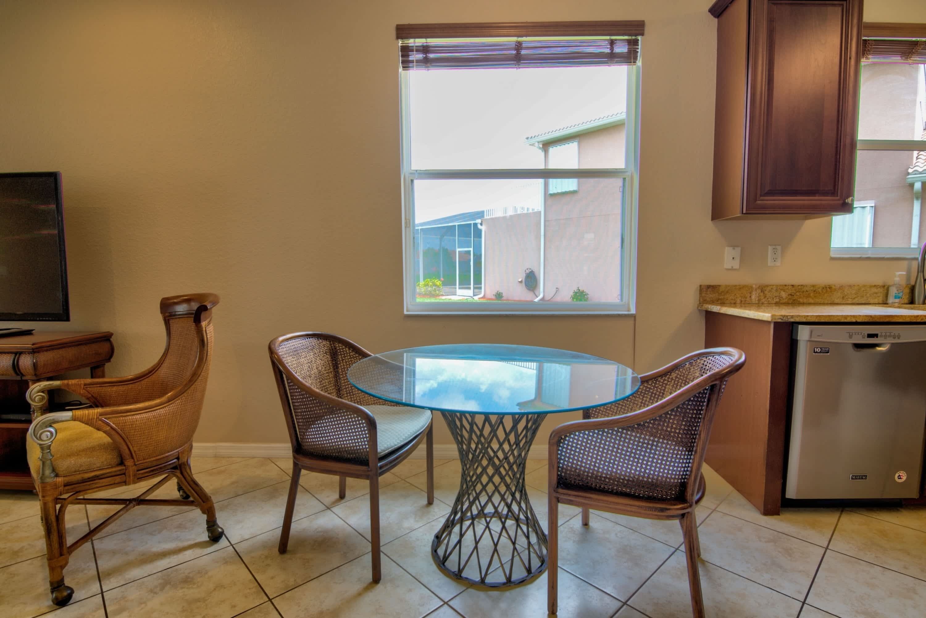 A kitchen with a dining table and chairs, a window, and a dishwasher.