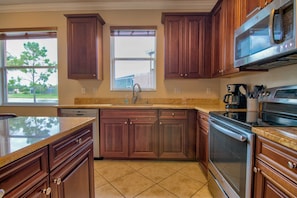 A kitchen with wooden cabinets, a stainless steel microwave, a coffee maker, and a dishwasher. - Fantastic Reflection Lakes Pool Home with Fabulous Views in Naples, Florida! (Naples)