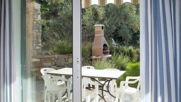 An outdoor patio with a table and chairs, a stone wall, and a clay oven. - Sylviane House (Pietrabruna)