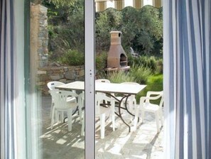 An outdoor patio with a table and chairs, a stone wall, and a clay oven. - Sylviane House (Pietrabruna)